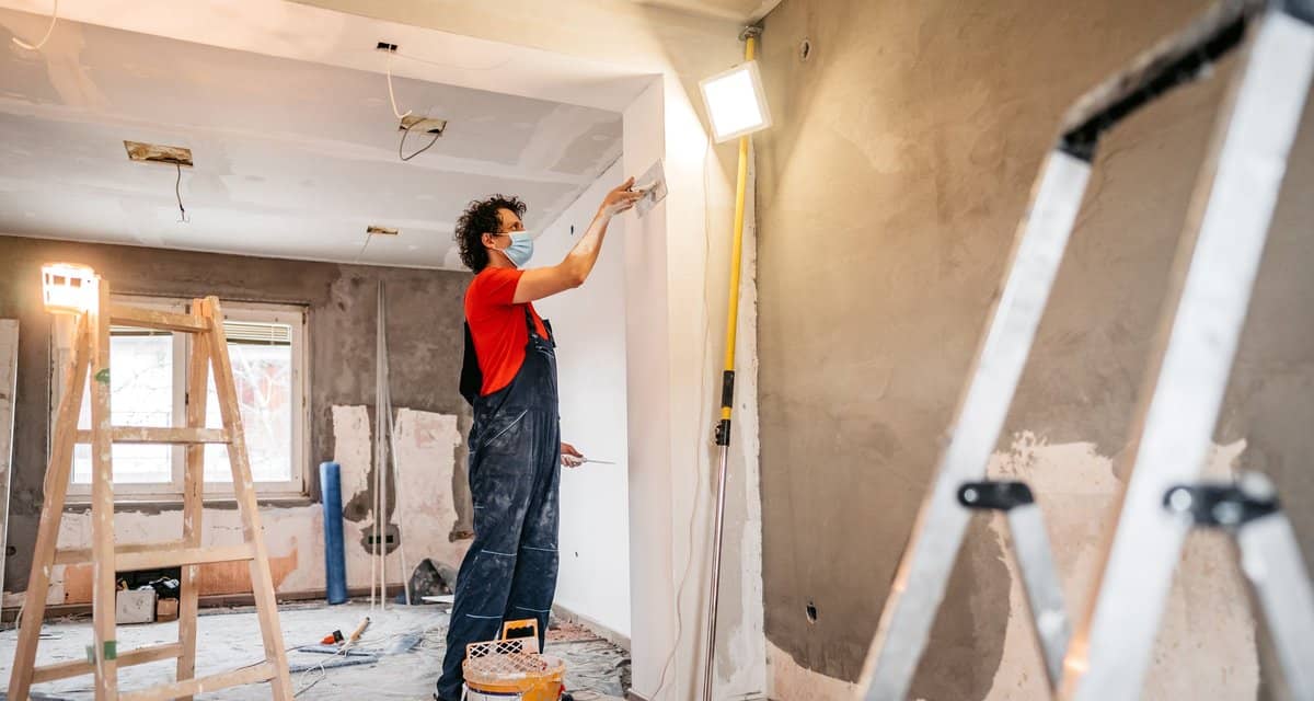 person putting up drywall in home renovation .width