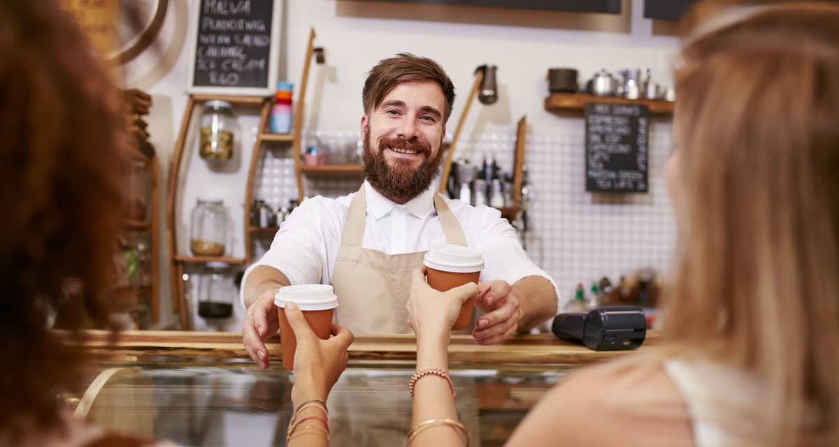 Smiling barista hands coffee to two women PAB.width .jpg