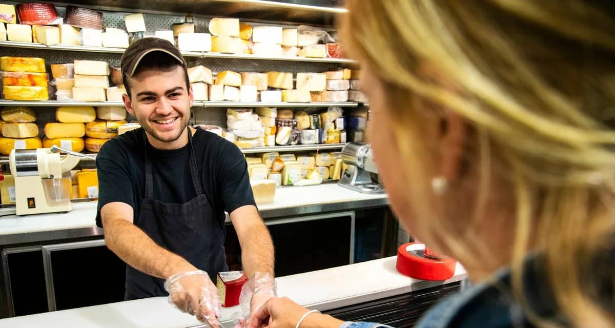 Employee handing sample of cheese to woman sh.width QAGKAOI.jpg