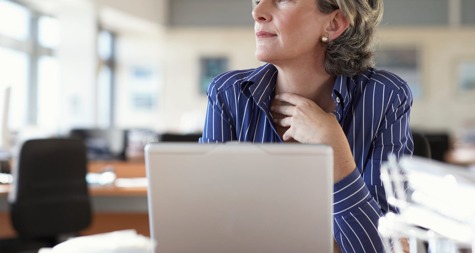 mature woman on laptop thinking and looking out window A52j1i
