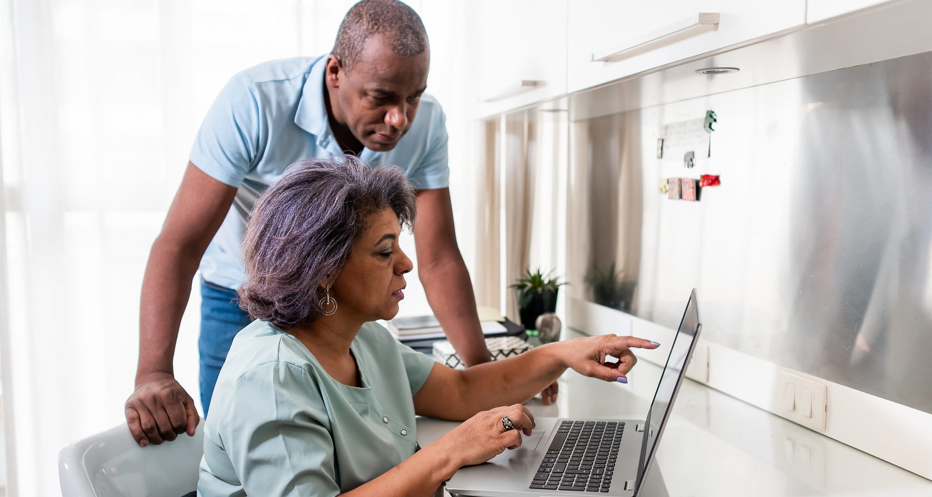 sitting person pointing at laptop with standing person behind them UwGFF