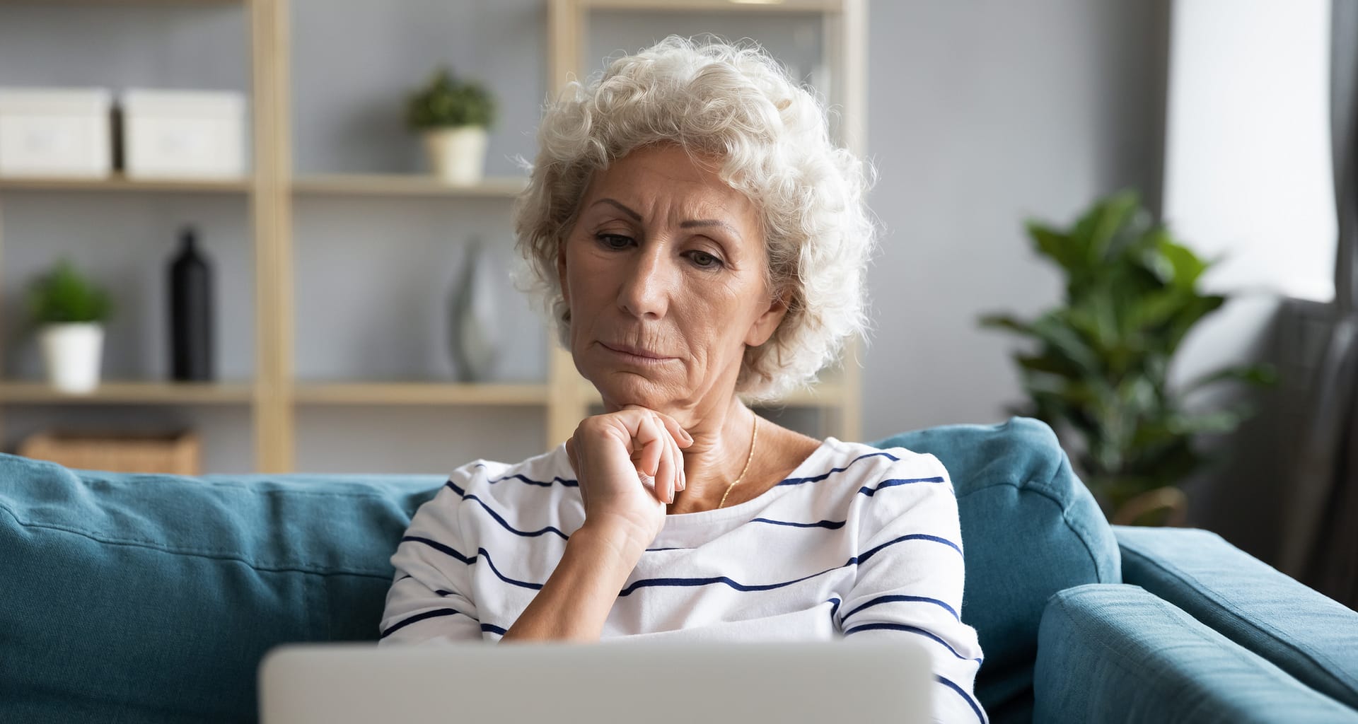 person with hand on chin looking at laptop SFkGg