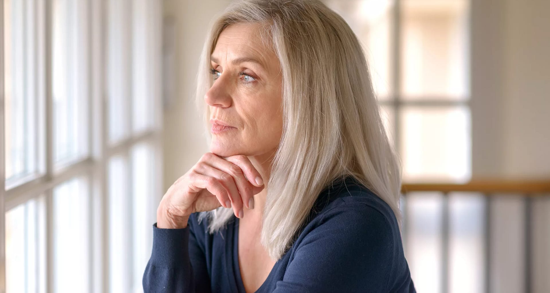 older person with serious expression looking out a window.jpg