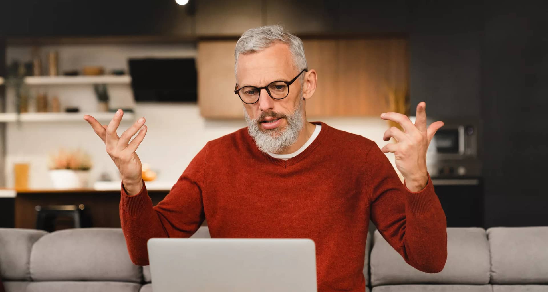 older man at laptop raising his arms as if frustrated.jpg