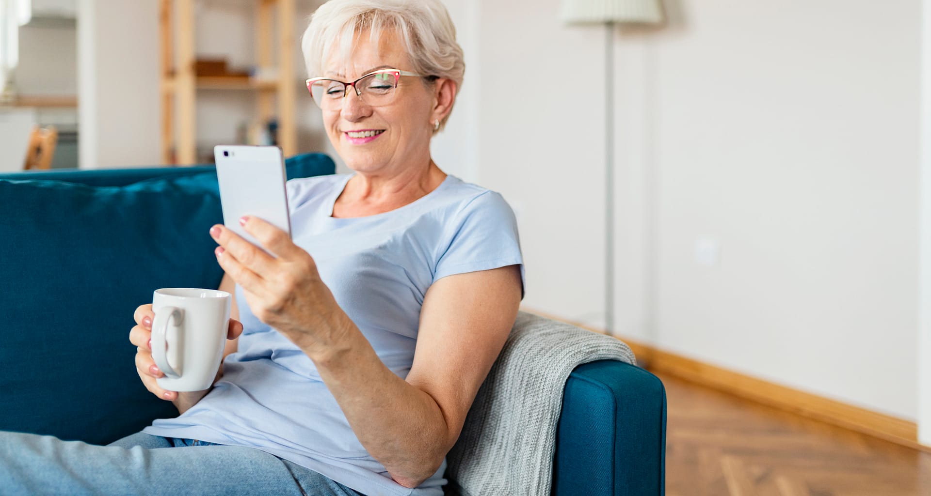 smiling senior holding coffee mug and looking at smartphone.jpg