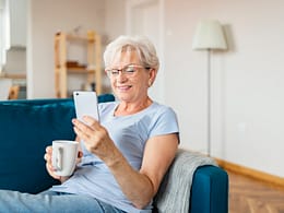 smiling senior holding coffee mug and looking at smartphone.jpg