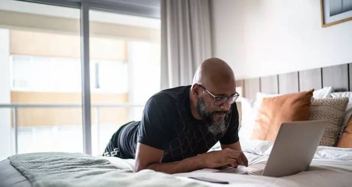 person lying on bed using laptop zxzVvg.width .jpg