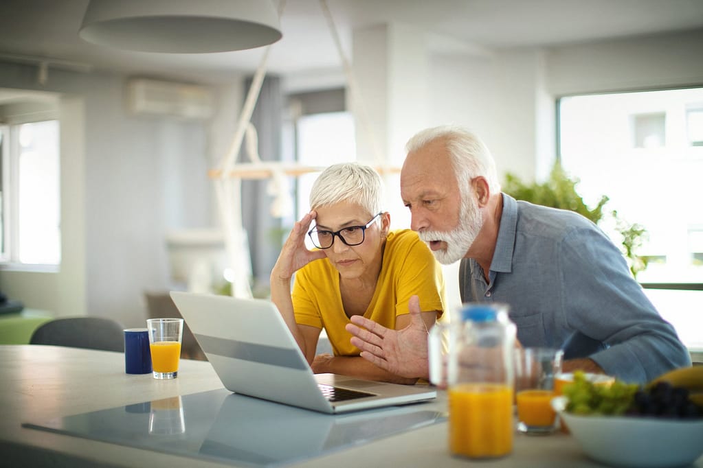 two people with stunned expressions looking at laptop