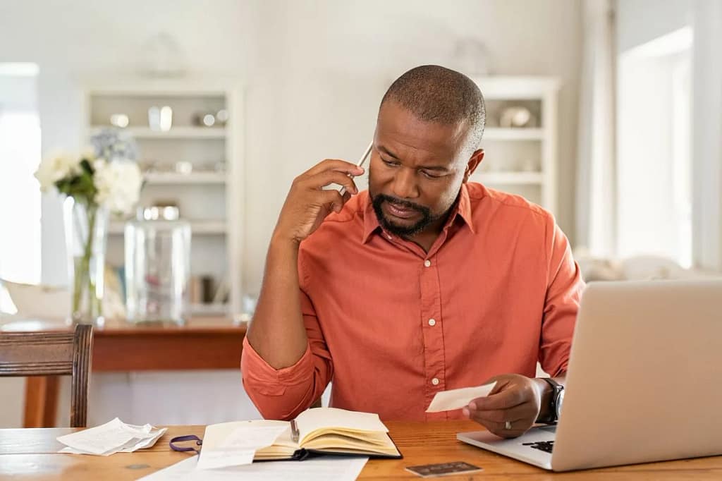 Man on phone with laptop documents qaawUT.width .jpg