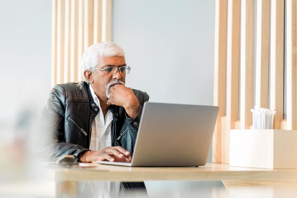 retired older man on laptop working reading news stocks