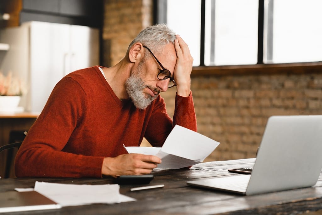 older man stressed holding document at laptop gettyimages