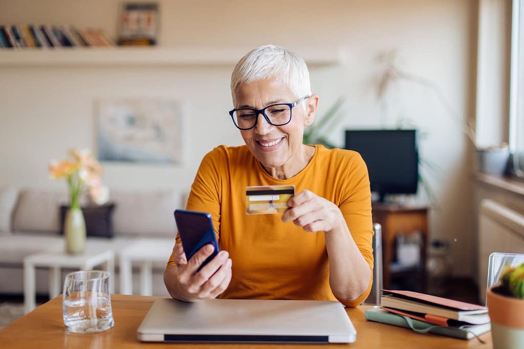 Mature woman smiling while holding credit car.width wrRdZh.jpg