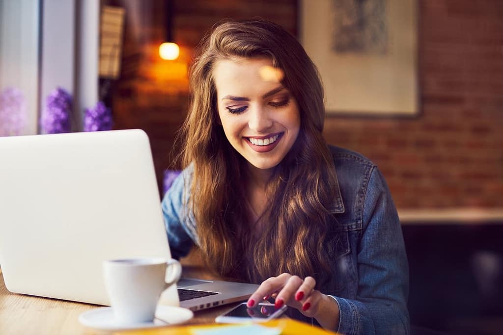 woman smiling with coffee and computer vkYiv.width .jpg