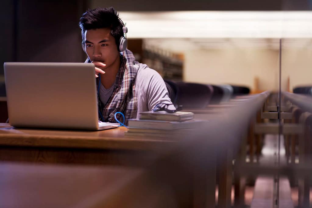 male college student a person at a laptop wearing headphones gettyimages .jpg
