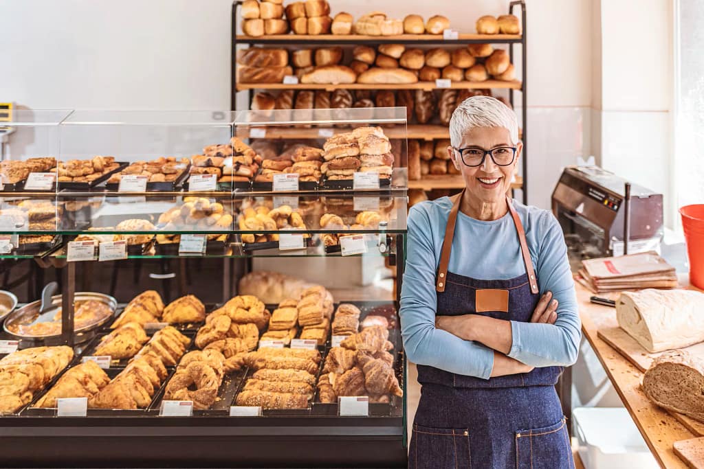 senior woman working a smiling person wearing an apron in a bakery gettyimages .jpg