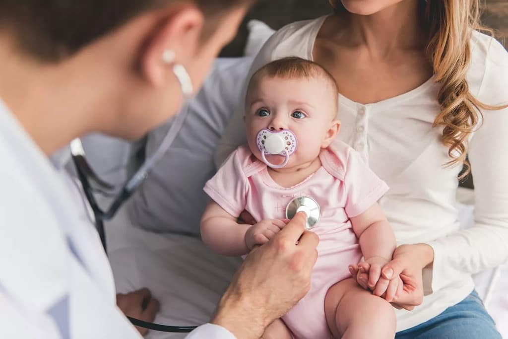 Baby in mothers lap staring up at doctor Byju.width .jpg