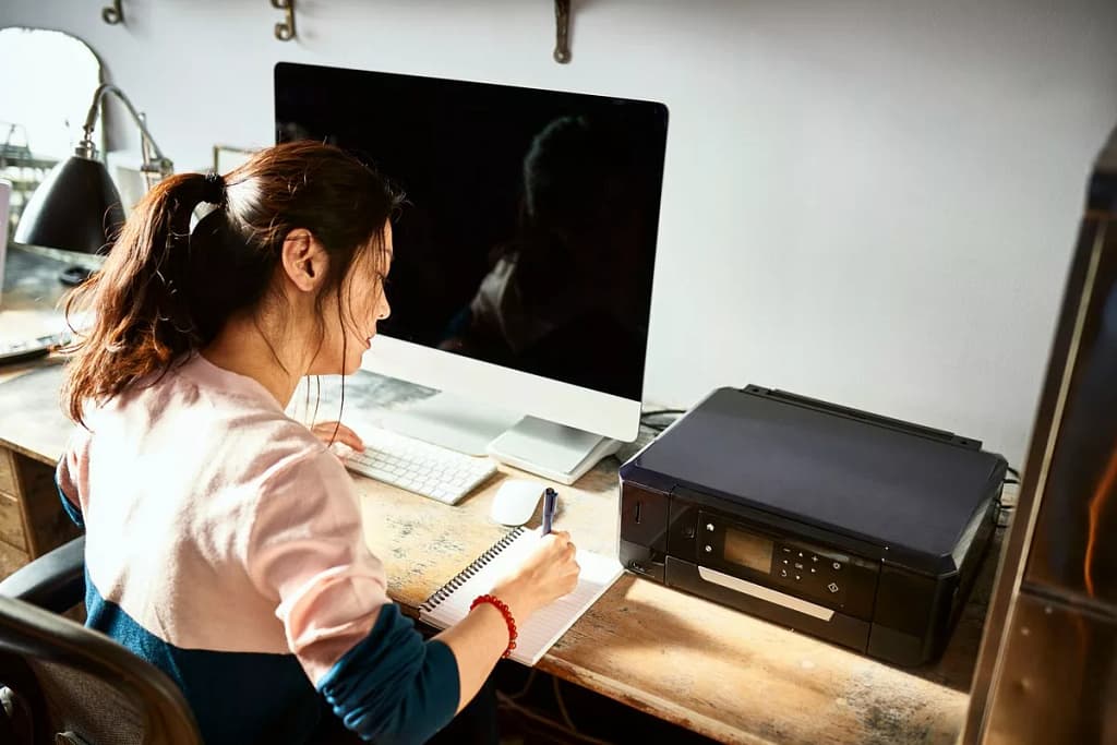 Woman writing in notebook at her home desk U.width .jpg
