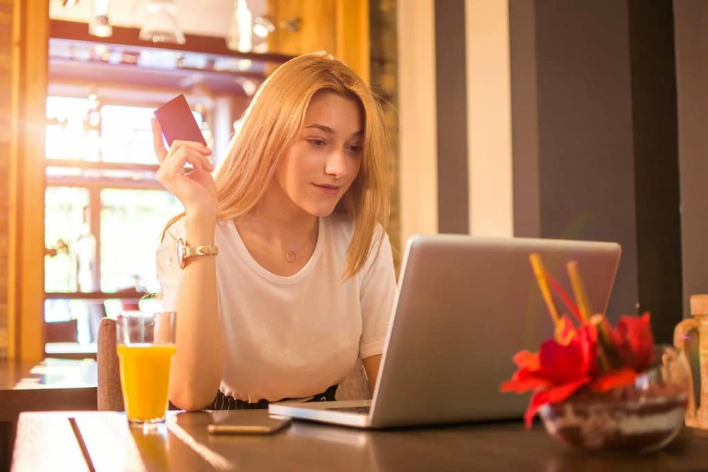 young adult woman at laptop holding credit ca.width xwXgoK.jpg