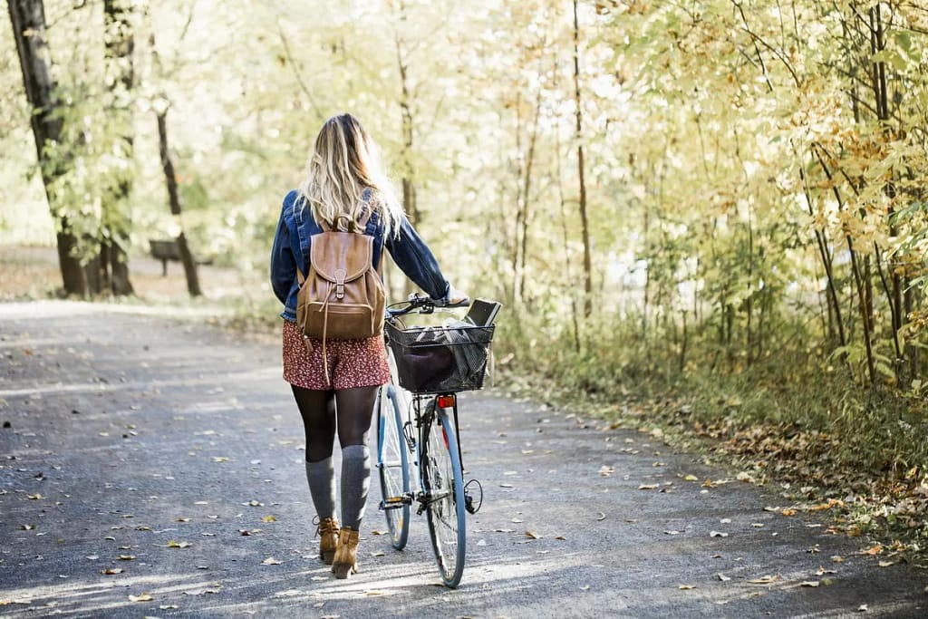 woman walking bike through park.width .jpg
