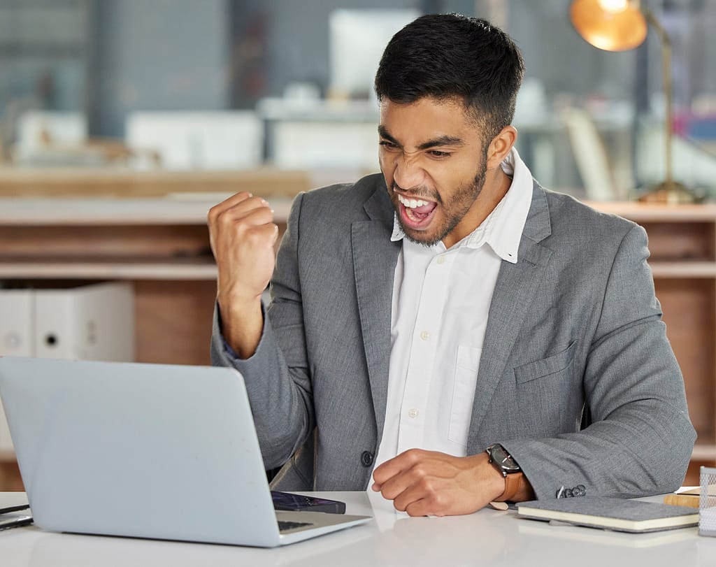 smiling person at laptop making celebratory fist gettyimages