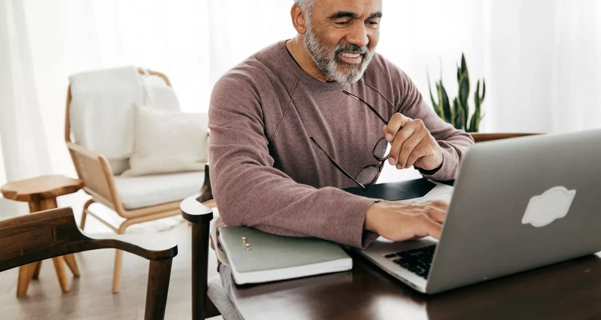 smiling person holding glasses and looking at laptop.jpg