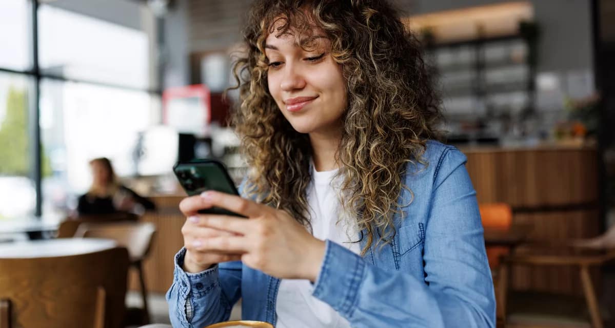 smiling person looking at smartphone in coffee shop.jpg