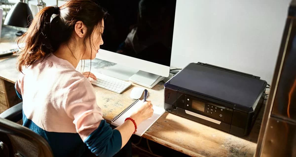 Woman writing in notebook at her home desk U.width .jpg