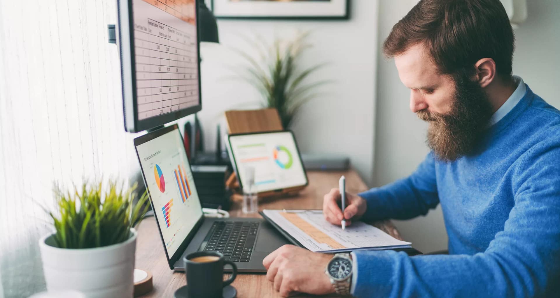 bearded person at desk by computer taking notes.jpg