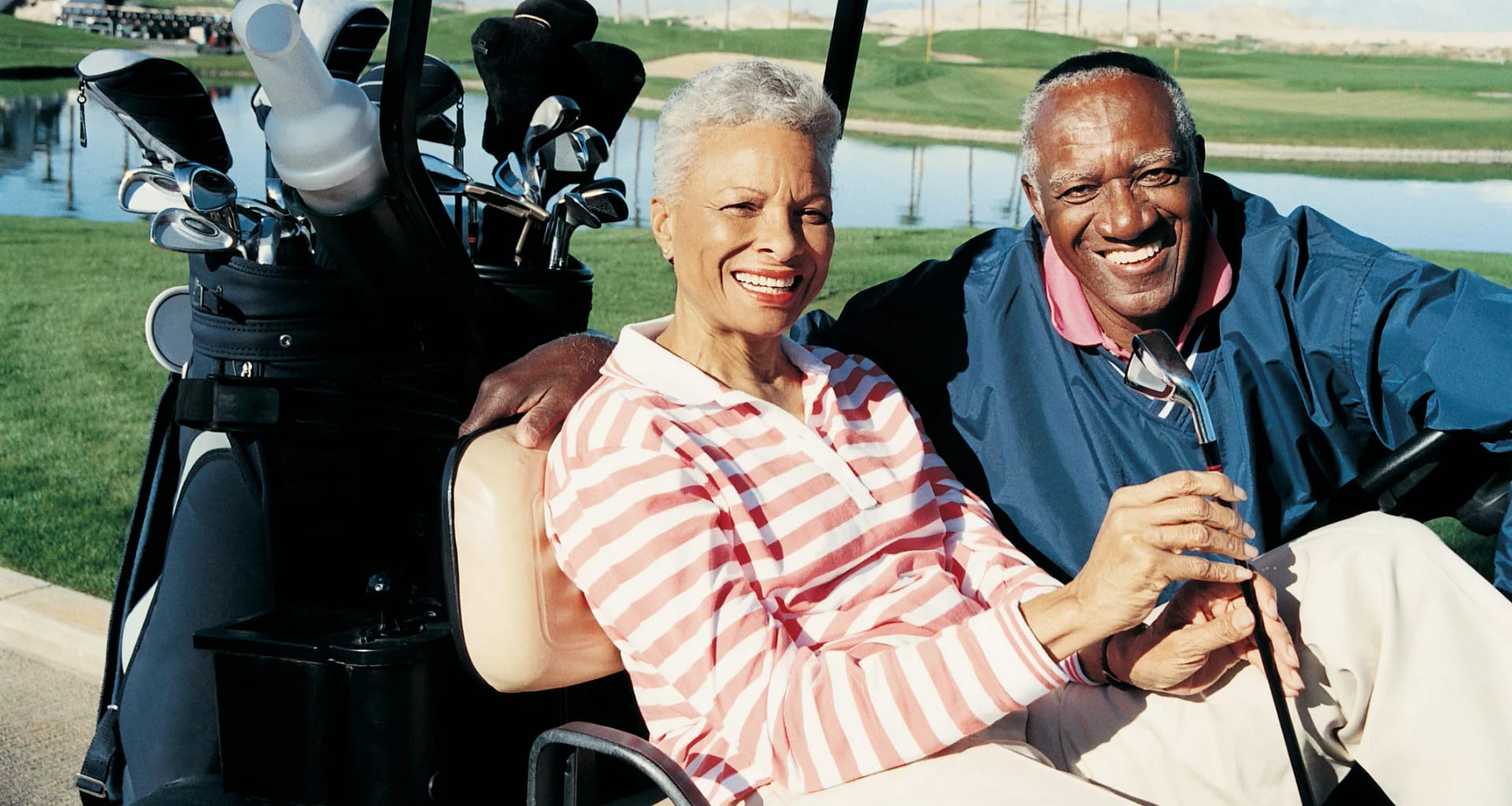 senior man and woman sitting in golf cart smiling poc.jpg
