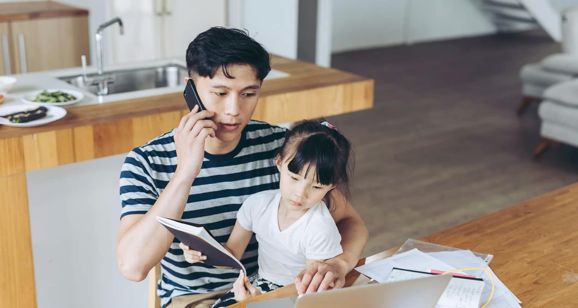 person talking on phone and looking at laptop with child on lap.jpg