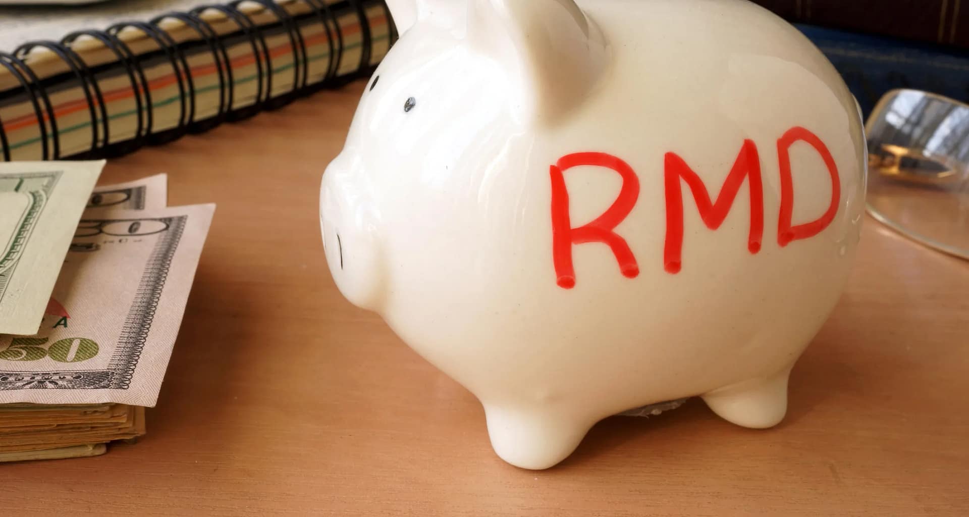 piggy bank with rmd written on its side next to stack of paper money retirement savings k ira cash.jpg