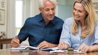 mature couple discussing finances with pens and paper