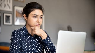 serious person with hand on chin looking at laptop