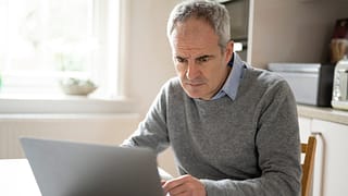 a person with a serious expression at a laptop gettyimages