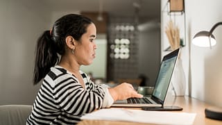 person sitting at desk and typing on laptop