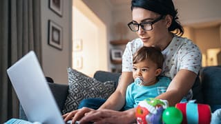person using laptop with baby in front of them