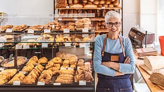 senior woman working a smiling person wearing an apron in a bakery gettyimages