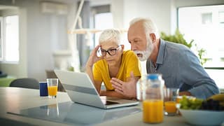 two people with stunned expressions looking at laptop
