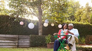 mature couple relaxing drinking wine together in their backyard