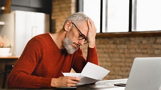 older man stressed holding document at laptop gettyimages