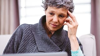 person with a worried expression looking at a laptop