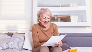 senior woman smiling reading document gettyimages