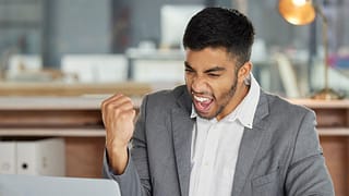 smiling person at laptop making celebratory fist gettyimages