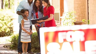 Couple and child in front of home for sale Tp.width