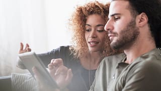 Couple looking at something together on a tab.width PsznaUo