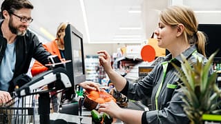 Grocery store employee ringing up customers .width
