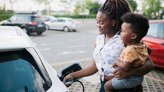 Mother holding her son while charging her ele.width