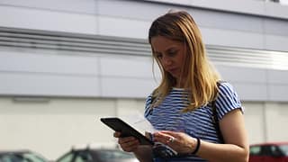 Woman in grocery store parking lot examining .width TGwgWbC