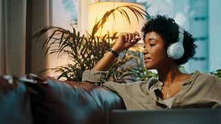 Woman listening to music through headphones. .width