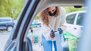 Woman loading car with groceries looks over h.width QbypC